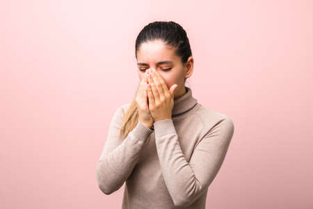 stop spreading coronavirus. young sick woman with fly or virus sneezing and coughing in a mask or napkin looking very hopeless.の写真素材