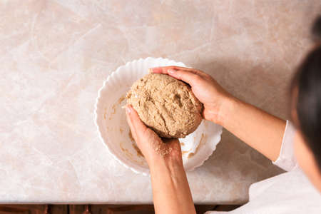 process of baking health bread at home. closeup woman hands kneading dough from rye flour on marble countertop in bright kitchen.の写真素材
