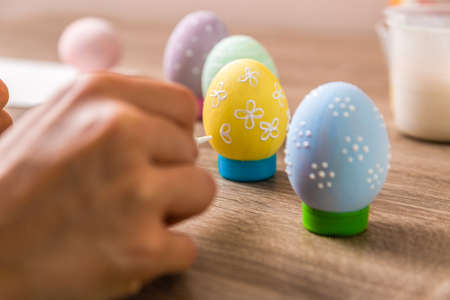 easter tradition. closeup child hands painting eggs in different colors on wooden table.の写真素材