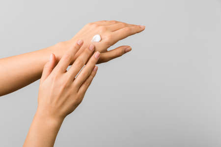 close up beauty shot of tender young woman hands applying moisturizer cold season skin protective cream.の写真素材