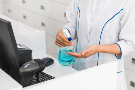 closeup hands of a medical worker or pharmacist using disinfectant, hand sanitizer in hospitalの写真素材
