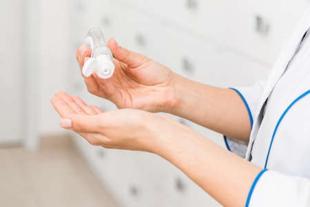 closeup hands of a medical worker or pharmacist using disinfectant, hand sanitizer in hospitalの写真素材