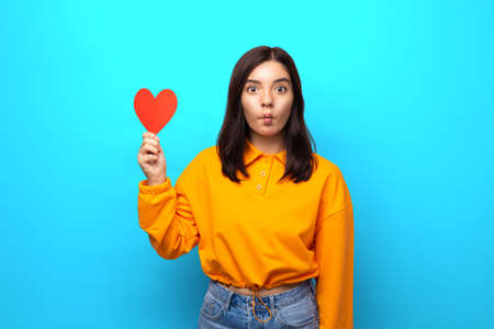 amazing mixed races woman with funny face holding up big heart-shaped valentineの写真素材
