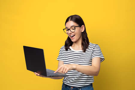 Attractive multi ethnicity female student in glasses happy expression using a laptop
