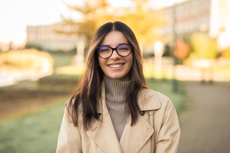 Cheerful LGBT female student wearing glasses joyfully smiling beautifully in front of campusの写真素材