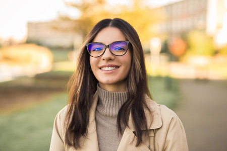 Close up portrait smiling newly admitted student multiethnic female wearing glasses in front of universityの写真素材