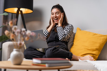 Positive emotions good news.Surprised student female video chatting on laptopの写真素材