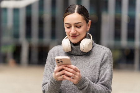 Work from anywhere, thrive everywhere. A remote freelancer in casual wear uses headphones and a phone to manage projects on the go, embracing the freedom of digital nomadismの写真素材