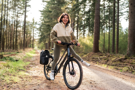 Woman cycling solo on a forest trail, capturing the spirit of active living and digital detoxの写真素材