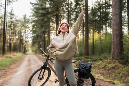 Nature Moves Her. Confident woman on a bike in the forest, recharging through adventure and healthy habitsの写真素材