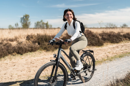Breezy journey as a smiling woman in airy clothes pedals through a sunny day, capturing the spirit of wellness and freedomの写真素材