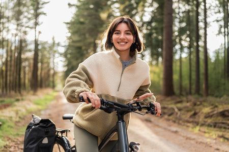 Riding into serenity, an adventurous woman embraces wellness and freedom on a sunset forest bike journeの写真素材