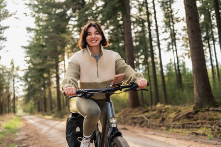 Solo cyclist coasts through green forest trails, blending summer vacation spirit with healthy lifestyle and nature-based sportの写真素材