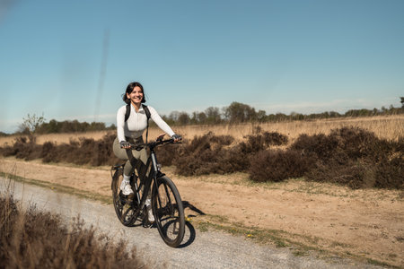 Woman biking across sun-drenched landscape, combining cycling sport with relaxed travel and summer vitalityの写真素材