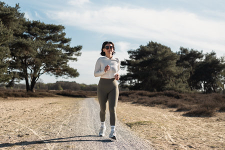 Focused woman jogging outdoors in nature, embracing wellness, mental clarity, and an active...