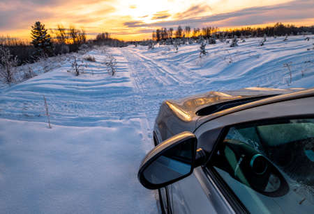 car goes through the snow in the woods. forest road in winter. frost on the trees. car close up at...