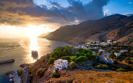 Greek port town with ships at sunset. sea and mountains in the evening sky.