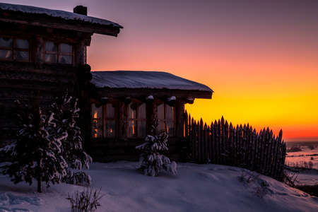Forest cabin and tree in winter. Wooden hut in the snow. Log house on the evening skyの写真素材