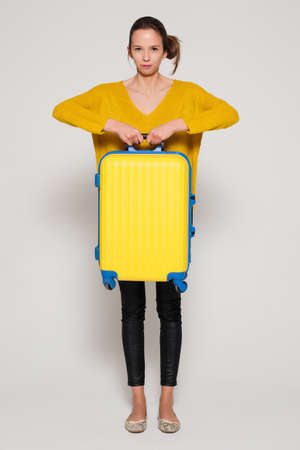 Beautiful sexy girl with a yellow suitcase loves to travelの写真素材