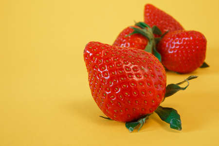 Macro shot - Delicious fresh strawberries on a yellow backgroundの写真素材