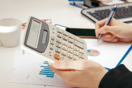 A young specialist works with financial documents at a computer.