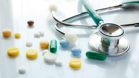 Stethoscope and multi-colored pills with reflection, medical conceptの写真素材