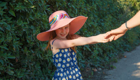 A girl in a big pink hat holds her mother by the hand. Parenting.の写真素材