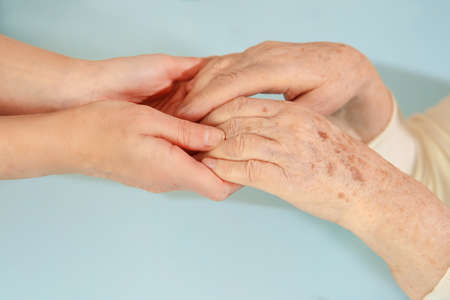 Helping hands, care for the elderly concept. On a blue backgroundの写真素材