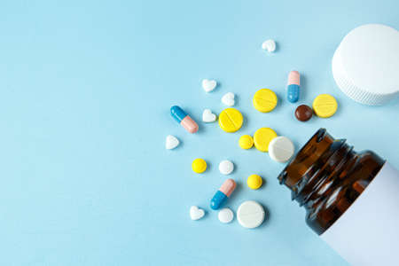 A pile of medical pills of different colors on a blue background. Healthcare and medicine concept.