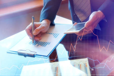 business documents on office table with smart phone and digital tablet and graph financial with...