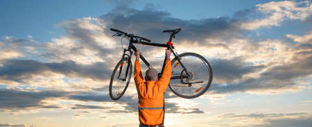 Biker silhouette against sunset sun as a concept of achievement, overcoming adversity and fulfilling...