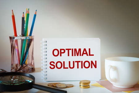 Business concept - workspace office desk and notebook writing OPTIMAL SOLUTION