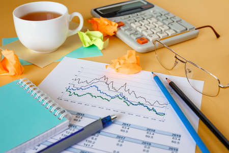 Desktop with documents, calculator and notepad. Documents with a graph deterioration. Crisis concept.の写真素材