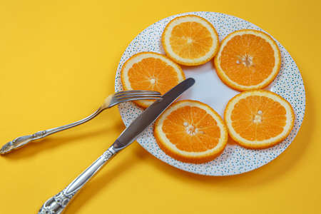 Orange slices on a plate and a knife with a fork. Diet conceptの写真素材