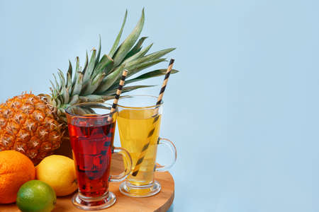 Fresh multifruit juice with ice in a glass. Pineapple, orange, banana, lemon, apple on a blue backgroundの写真素材