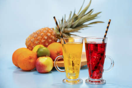 Fresh multifruit juice with ice in a glass. Pineapple, orange, banana, lemon, apple on a blue...