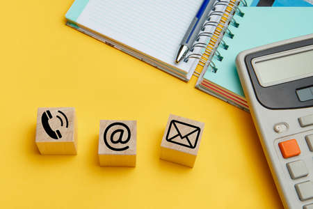 Website and internet contacts icons on wooden cubes on yellow backgroundの写真素材