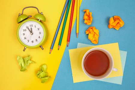 Office desk with an alarm clock and a cup of tea. Time for a tea break.の写真素材