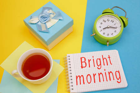 Cup of tea, the inscription Bright morning and an old-style alarm clock.