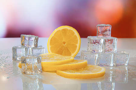 Melting ice with reflection and slices of lemon on the background of multi-colored lights.の写真素材