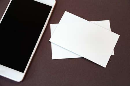 Mock up of blank business card and black smartphone screen on tableの写真素材