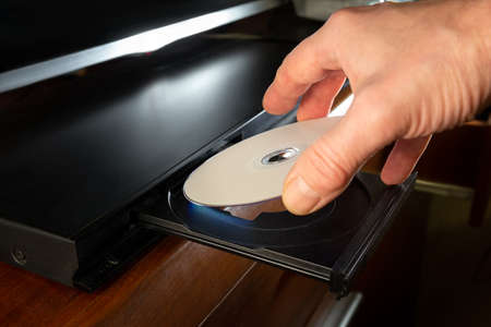 hand holding dvd-disk insert to dvd playerの写真素材