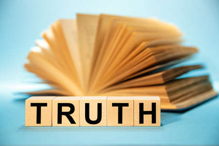 Wooden cubes with the abbreviation TRUTH on the background of an open book.の写真素材