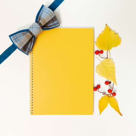 Mock-up blank for a banner or design on an autumn theme - a bow tie, a notebook and yellow leaves.