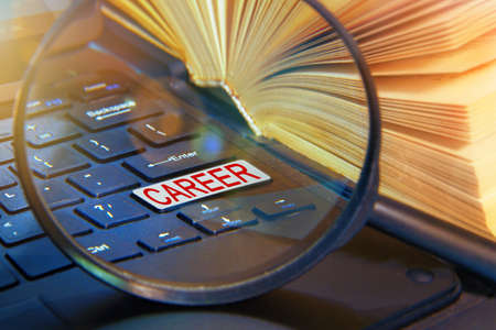 A laptop computer with a magnifying glass. CAREER word written on a computer button.の写真素材