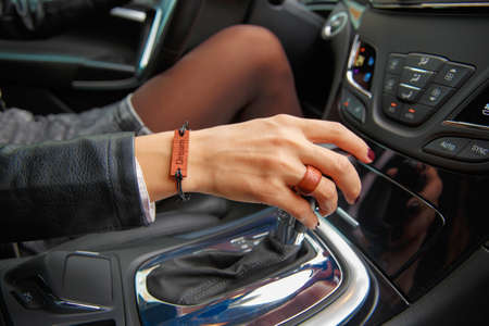 Shooting concept: girl s hands on the steering wheel of a car, a bracelet with the inscription dream...