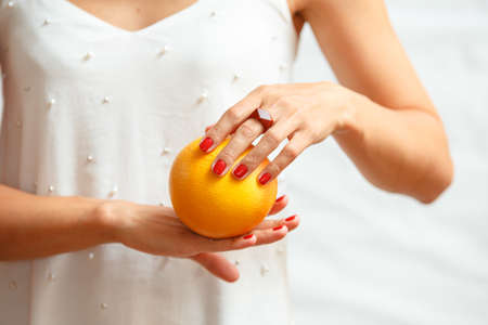 Hands of a young woman holding a red grapefruit. healthy food concept