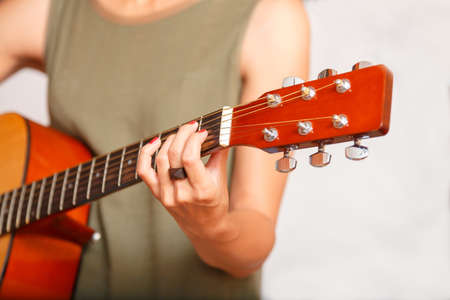 A girl's hand as she hold an acoustic guitar by the neck