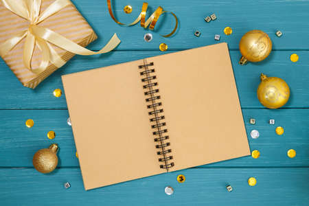 Wooden blue background and golden christmas decorations and gifts. Craft notebook for inscriptions...