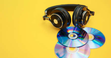 Headphones and music discs on a yellow background. Musical concept.の写真素材